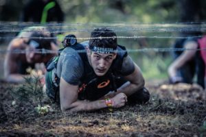 Man in a Spartan race crawling under barbed wire