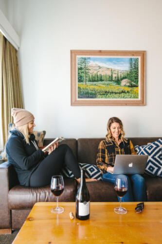 Two people sitting on a couch, one on a laptop